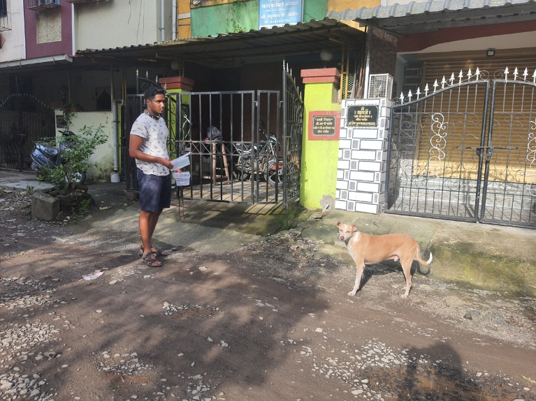 Nakul Wewhare holding field notes while observing a free-ranging dog on a street in Mumbai.