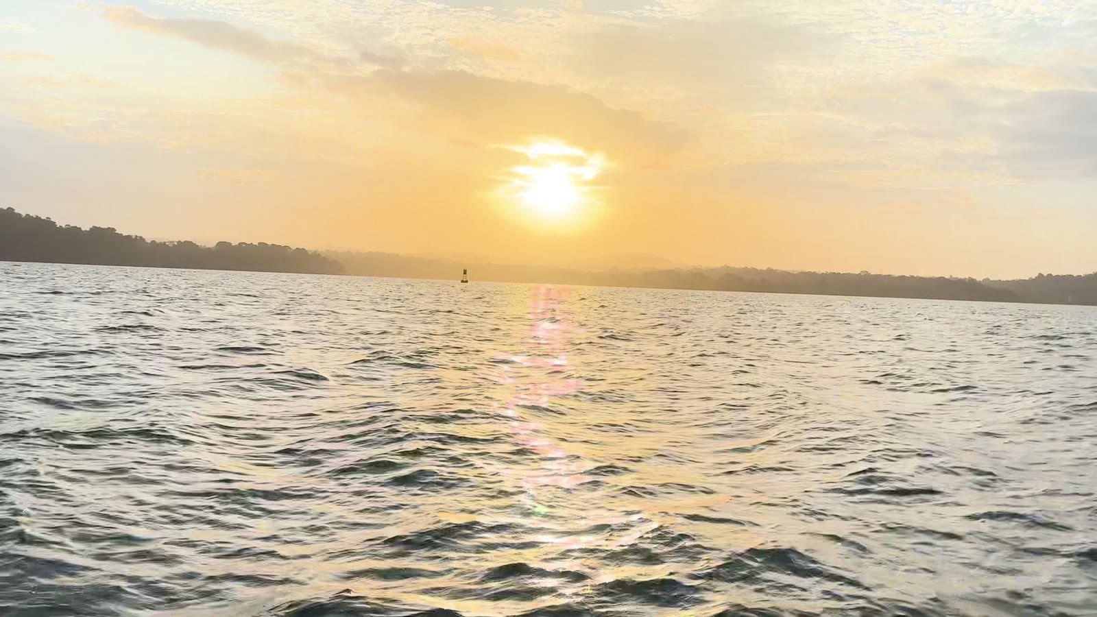 Sunrise glows above rippling water and forested shores on Gatun Lake near Gamboa.